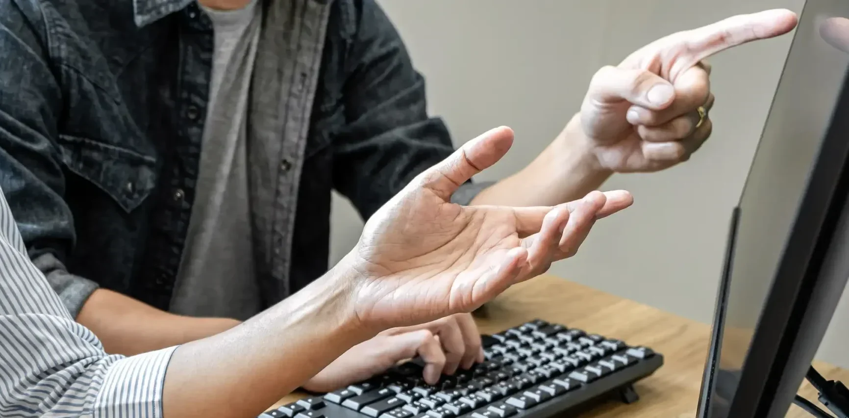 Dos personas trabajando juntas en un ordenador representando la gestión profesional de una agencia de OnlyFans trans