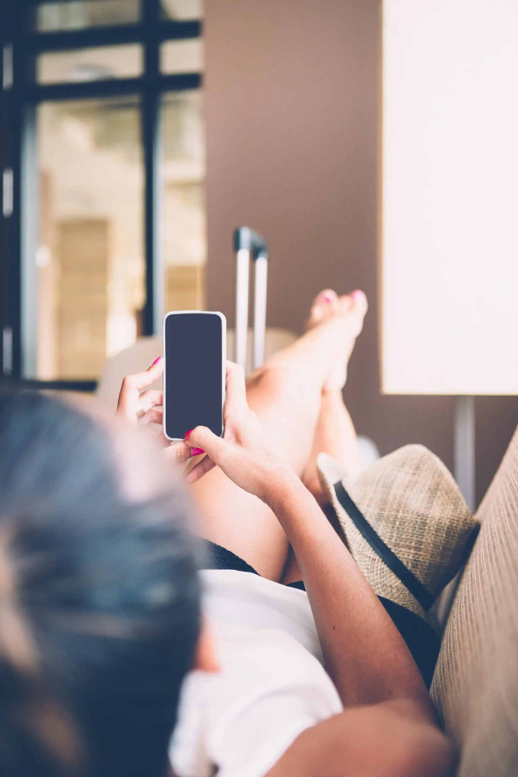 Mujer relajada en el sofá usando el móvil, representando la facilidad de contactar con la agencia OnlyFans trans