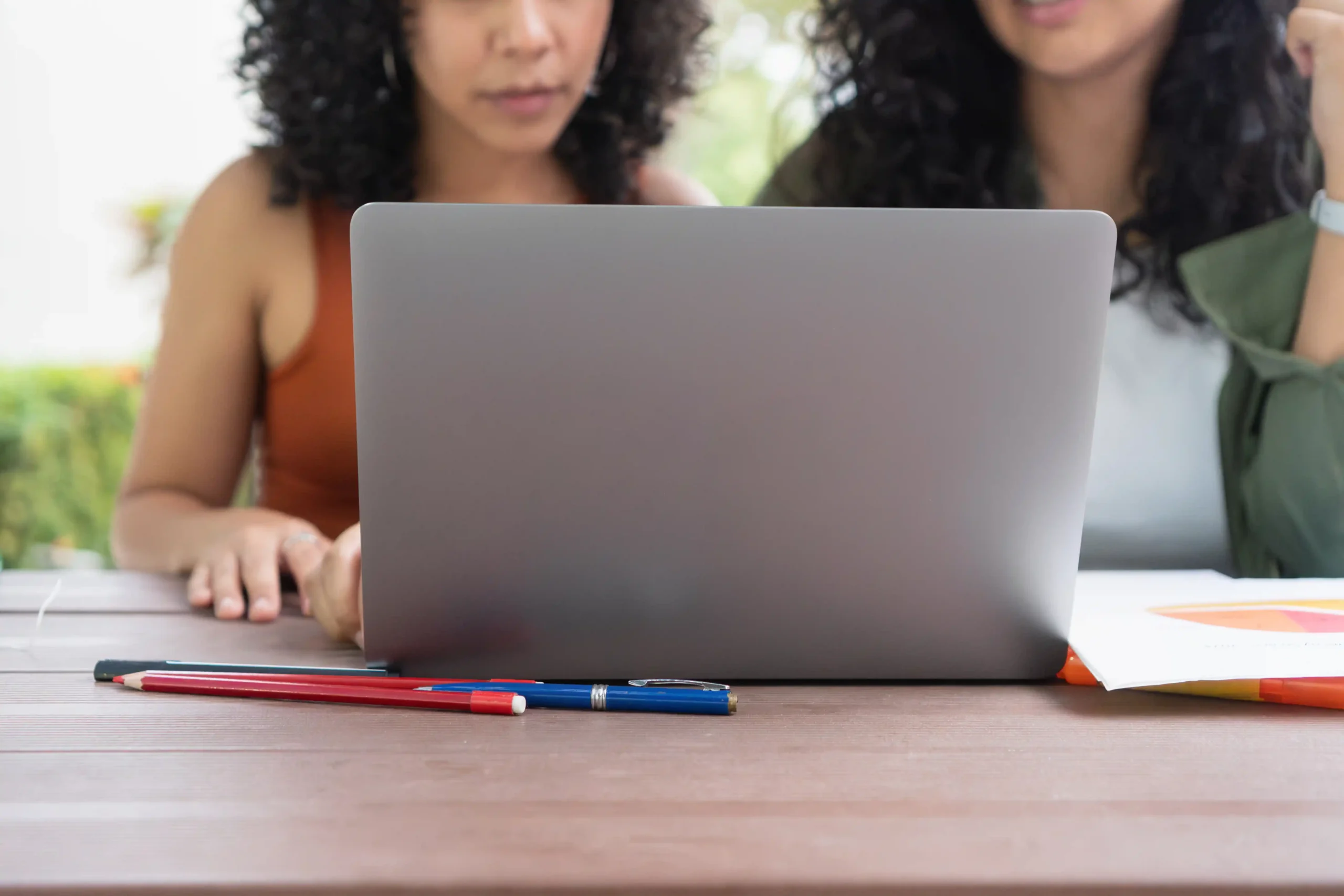 Dos mujeres del equipo OFM Trans trabajando juntas en el portátil, planificando estrategia para creadoras trans