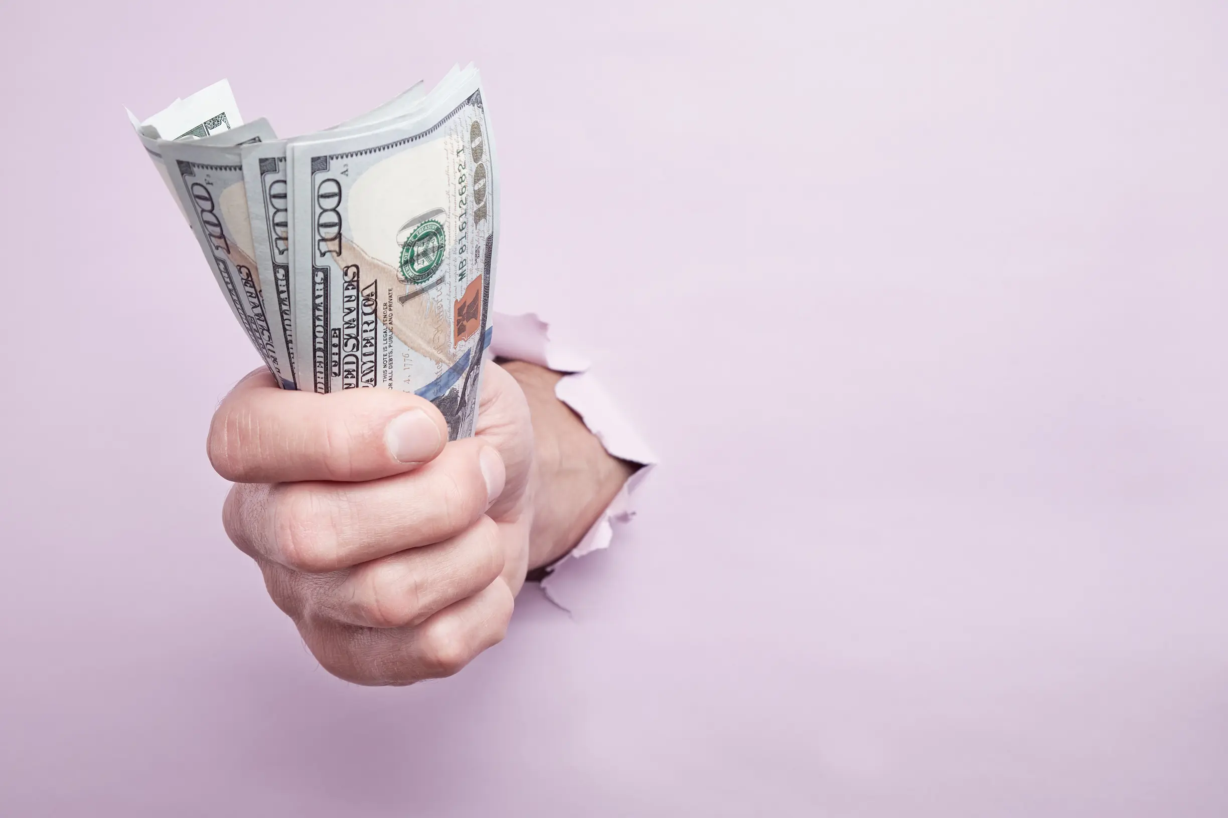 Mano sosteniendo billetes de dólar representando las ganancias de una creadora trans en OnlyFans con gestión profesional