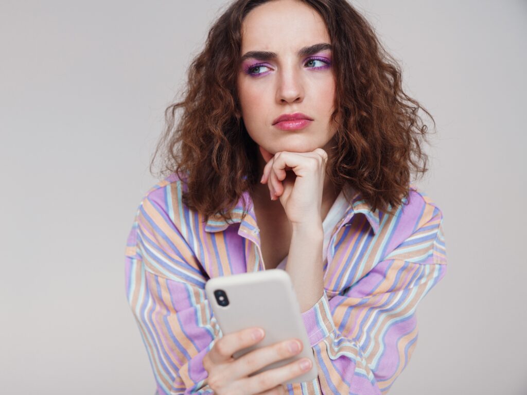 Creadora trans pensativa mirando el móvil mientras decide contratar una agencia OnlyFans trans